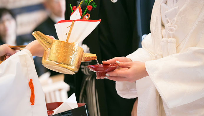 花嫁の持つ盃に巫女がお神酒を注ぐ